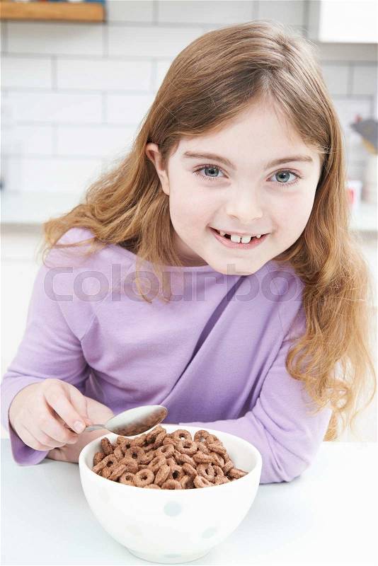 Girl Eating Bowl Of Sugary Breakfast Cereal In Kitchen, stock photo