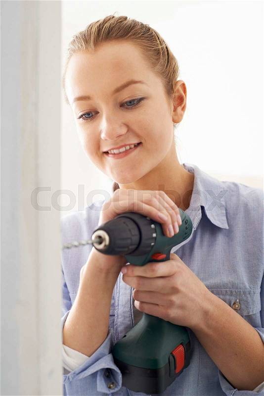 Young Woman Using Electric Drill In House Rennovation Project, stock photo