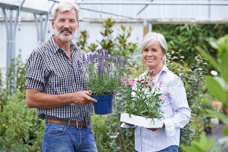 Mature Couple Choosing Plants At Garden Center, stock photo