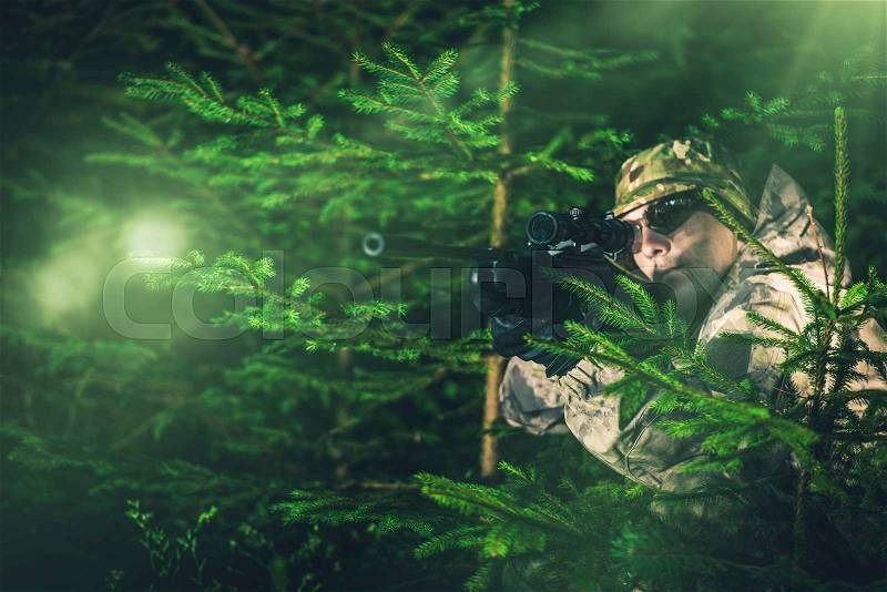Hunting Poacher in Dense Pine Forest. Hunter in Camouflage with Hunting Rifle, stock photo