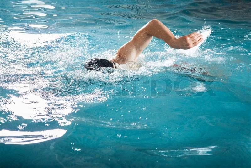 Young man swimming the front crawl in a pool, stock photo