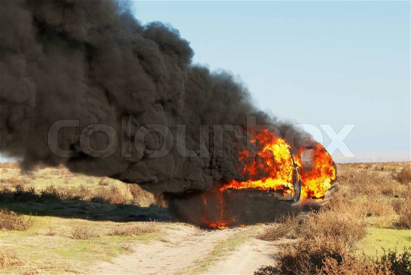 Car fire on desert rural road, stock photo