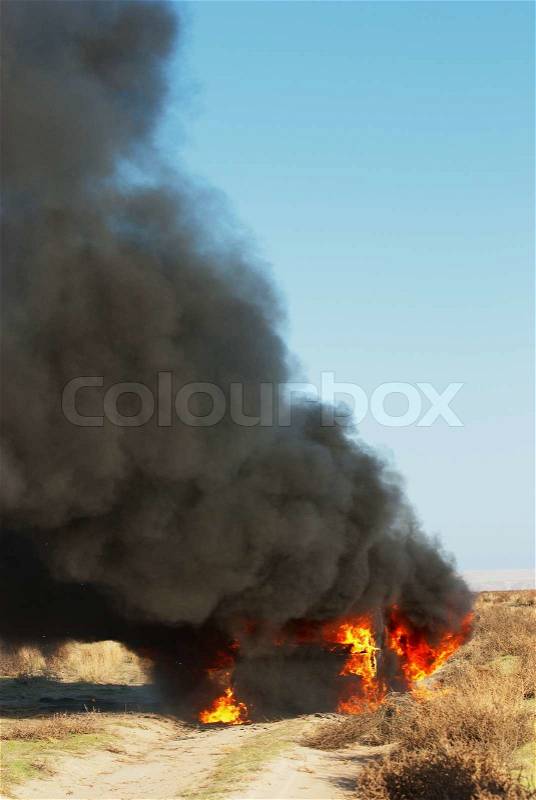 Car fire on desert rural road, stock photo