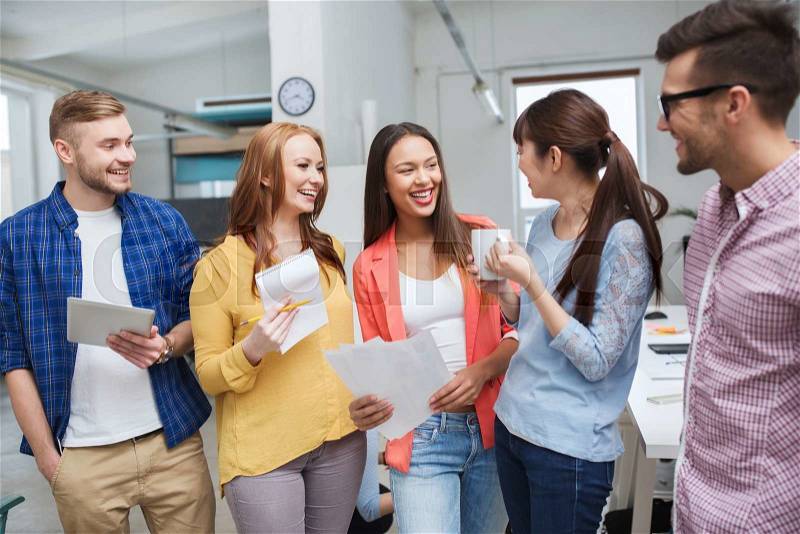 Business, communication, startup and people concept - happy international creative team or students on coffee break talking at office, stock photo