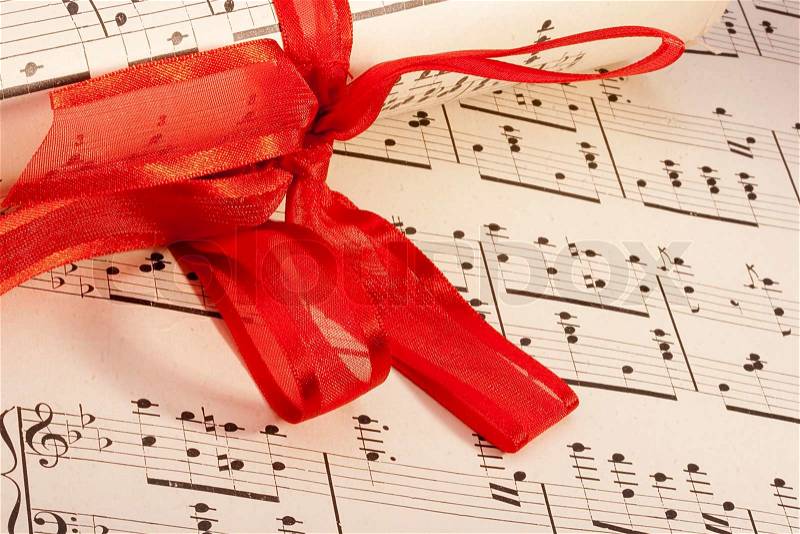 Theme music, old musical notes with roll bandaged red ribbon, stock photo