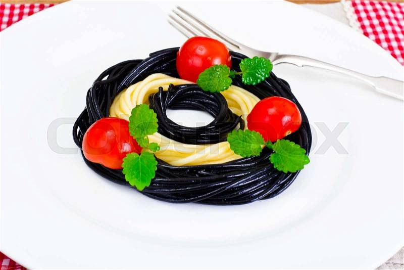 Black Spaghetti with Cuttlefish Ink, Tomato and Basil. Mediterranean and Asian Cuisine. Studio Photo, stock photo