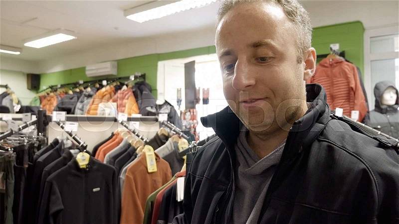 Man shopping for clothes and speaks to sales manager or cashier in a clothing store shop. , stock photo
