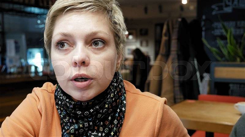 Pretty blond short hair woman talks to her friend with emotions and expression in a bar cafe restaurant. , stock photo