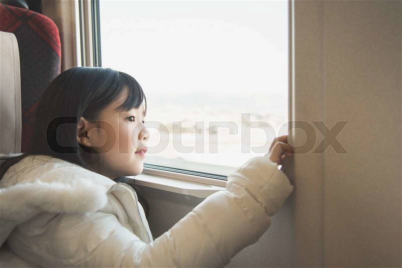 Little asian girl looking through window. She travels on a train,vintage filter, stock photo