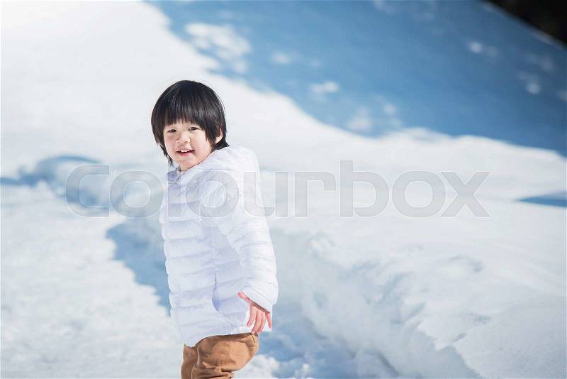 Portrait of asian boy in winter clothes with snow background, stock photo