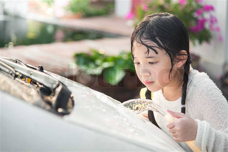 Beautiful asian child washing car in the garden, stock photo