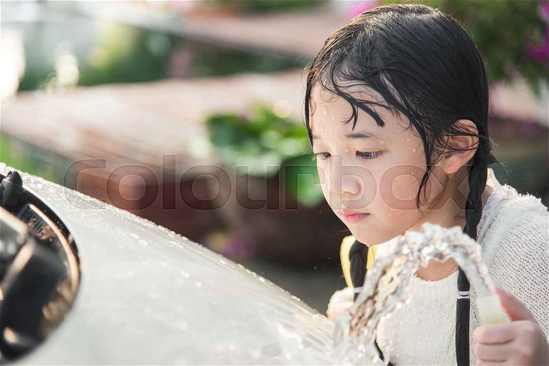 Beautiful asian child washing car in the garden, stock photo