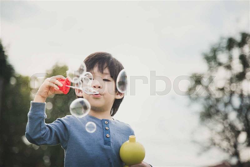 Cute asian child is blowing a soap bubbles,vintage filter, stock photo