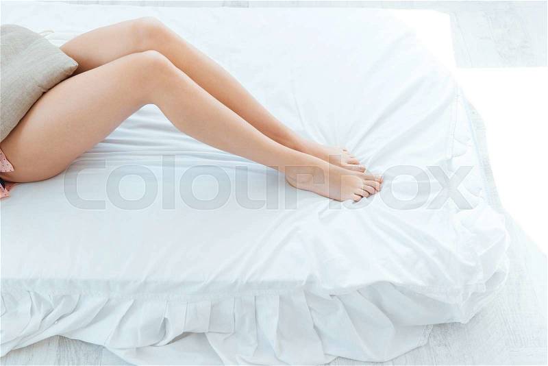 Beautiful slim legs of young woman lying in bed , stock photo
