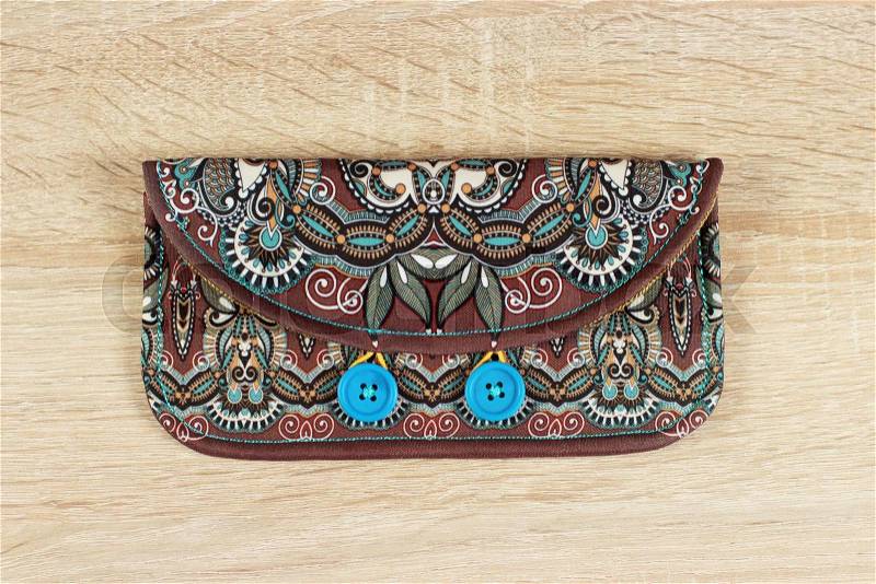female purse money artist\'s design with two wooden buttons on wood background, handmade floral paisley pattern, stock photo