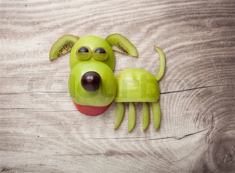 Dog made of apple, kiwi and grape on wood background, stock photo