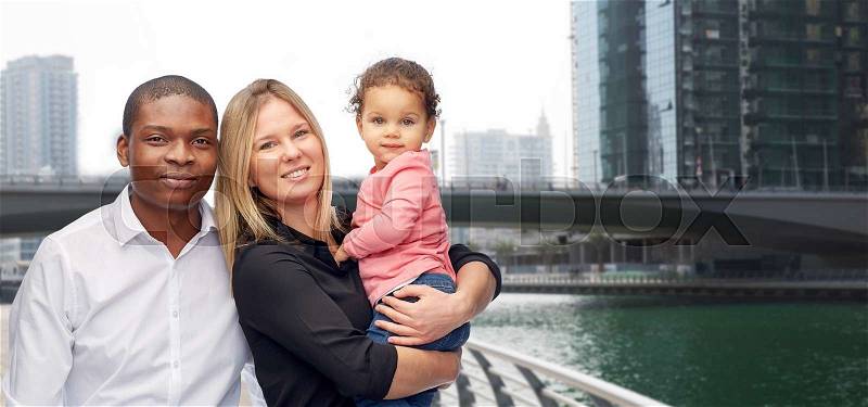 Family, travel, tourism and international concept - happy multiracial mother, father and little child over dubai city street background, stock photo