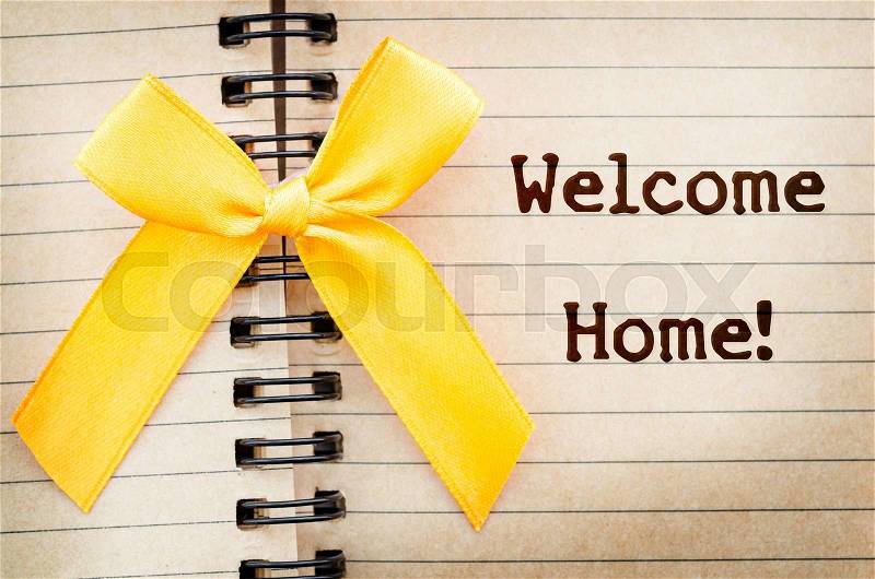 The words Welcome Home written on a old brown diary paper next to a yellow ribbon,in reference to military returning from overseas duty, stock photo