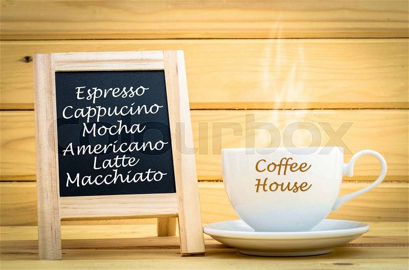 Menu coffee on black chalkboard with hot coffee in white cup and smoke in on wooden room, stock photo