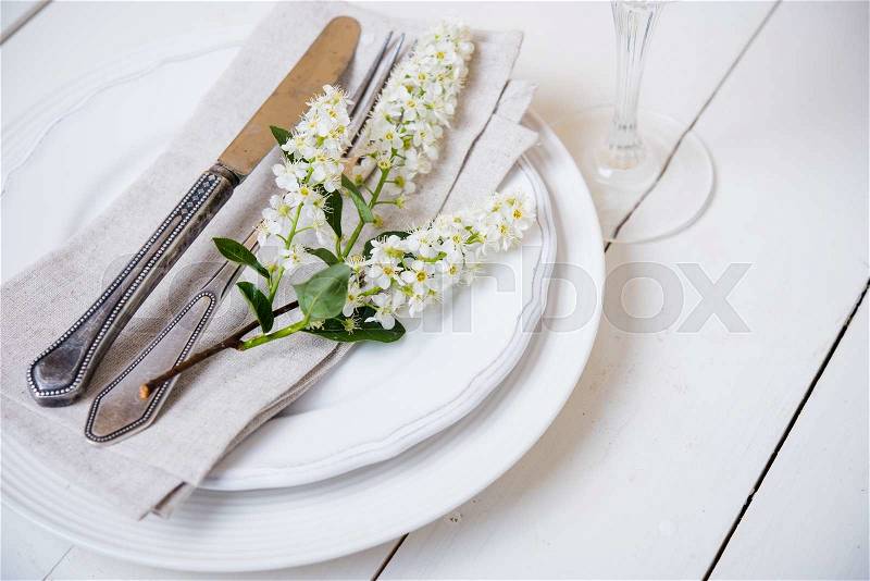 The snow white wedding table decor with bird cherry blossoms and cutlery, vintage rustic wedding table setting, stock photo