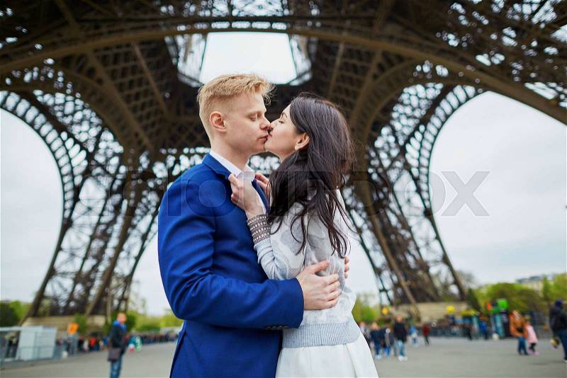 Romantic couple kissing just under the Eiffel tower, stock photo