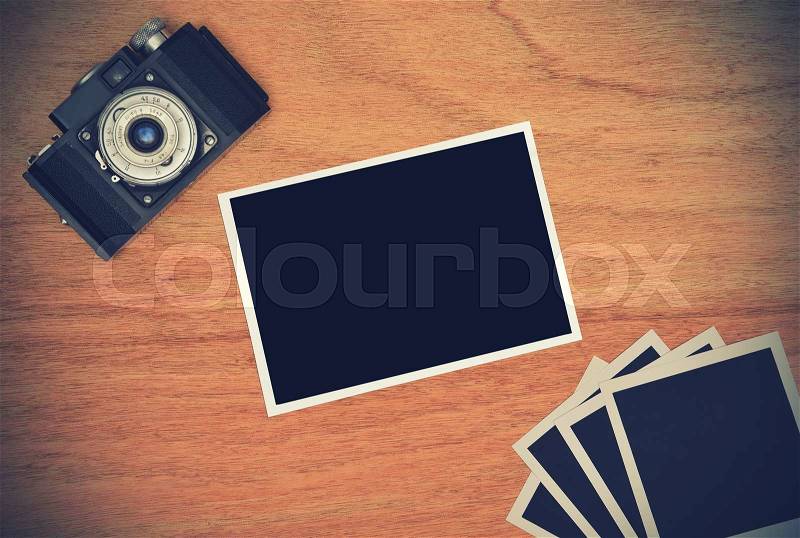 Retro camera with four blank photo card on wooden table. Vintage effect, stock photo