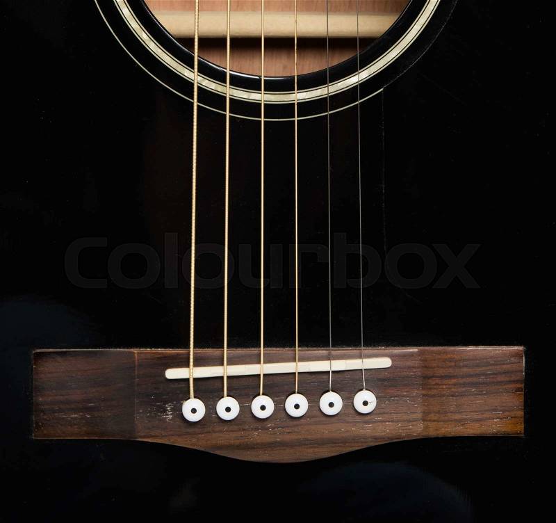 Detail of an acoustic black guitar with the strings and the sound hole, stock photo
