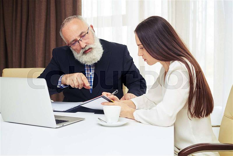 Young businesswoman and senior man with beard working and planning in the meeting, stock photo