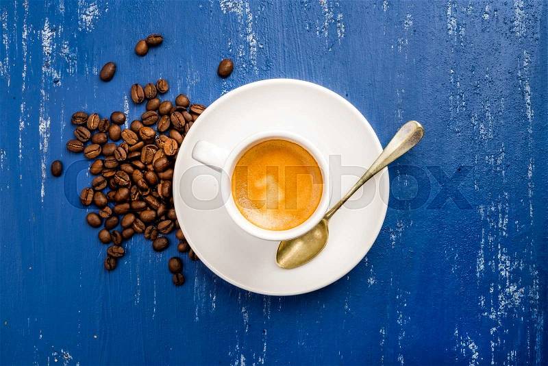 Cup of espresso coffee and beans on wooden blue painted table background. Top view, stock photo
