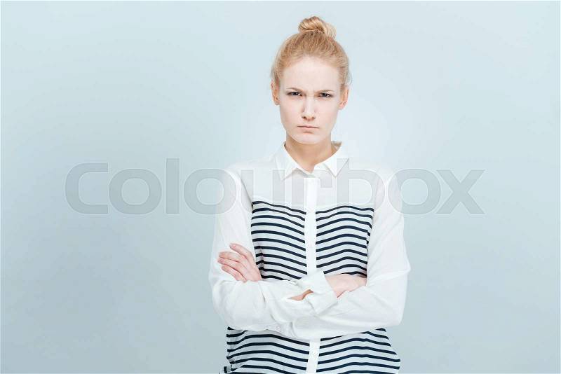 Angry woman with arms folded standing isolated on a white bakground, stock photo