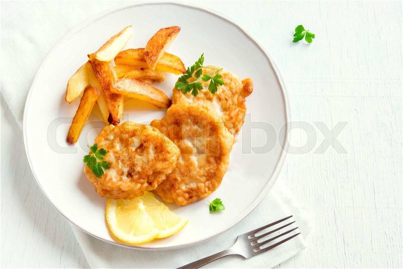Homemade fish cakes with french fries over white wooden background with copy space, stock photo