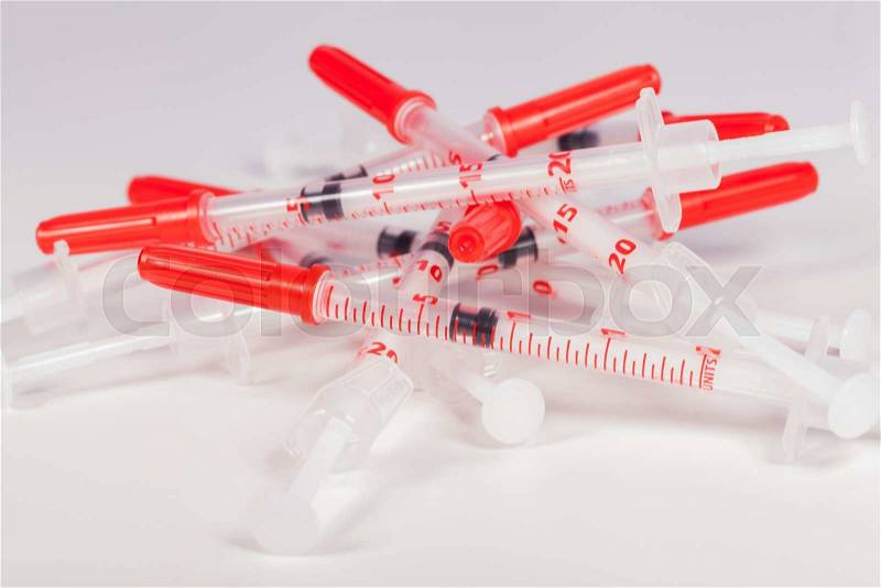 Still Life Close Up of Pile of Empty Syringe Needles with Red Safety Caps in Studio with White Background, stock photo