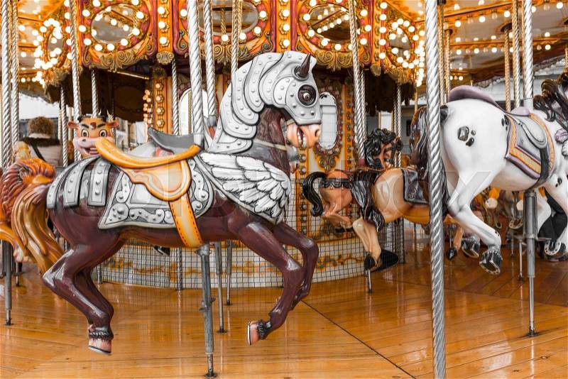 Old French carousel in a holiday park. Three horses and airplane on a traditional fairground vintage carousel. Merry-go-round with horses. , stock photo