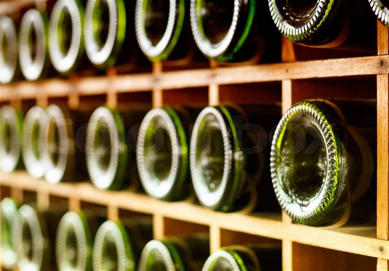 Wine bottles stacked on wooden racks, stock photo