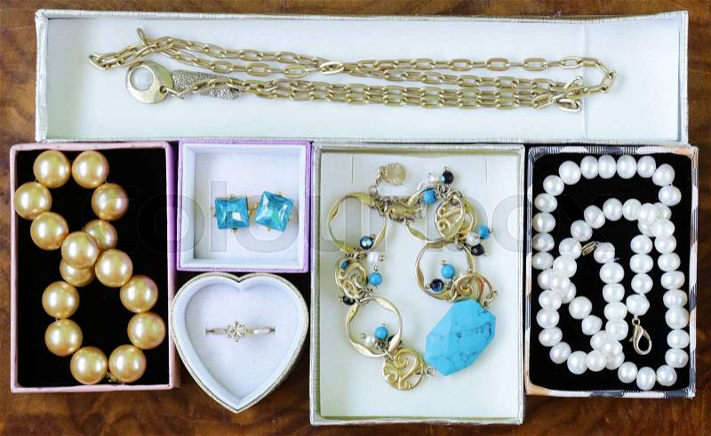 Necklaces, rings, earrings, pearls and gold in boxes on a wooden background, stock photo