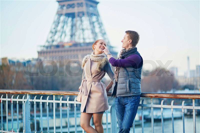 Young romantic couple near the Eiffel tower in Paris, France, stock photo