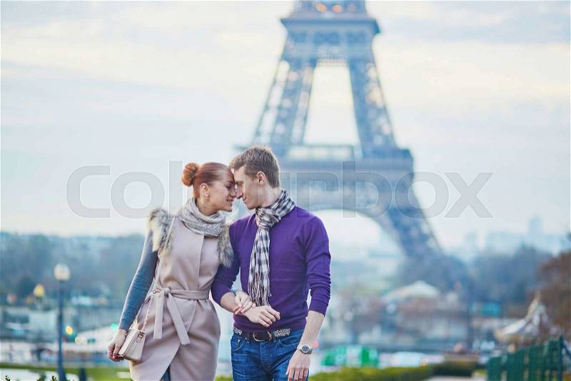 Young romantic couple near the Eiffel tower in Paris, France, stock photo