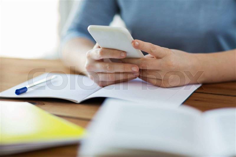 High school, education, people and learning concept - close up of young student or woman with smartphone and book writing to notebook at home, stock photo