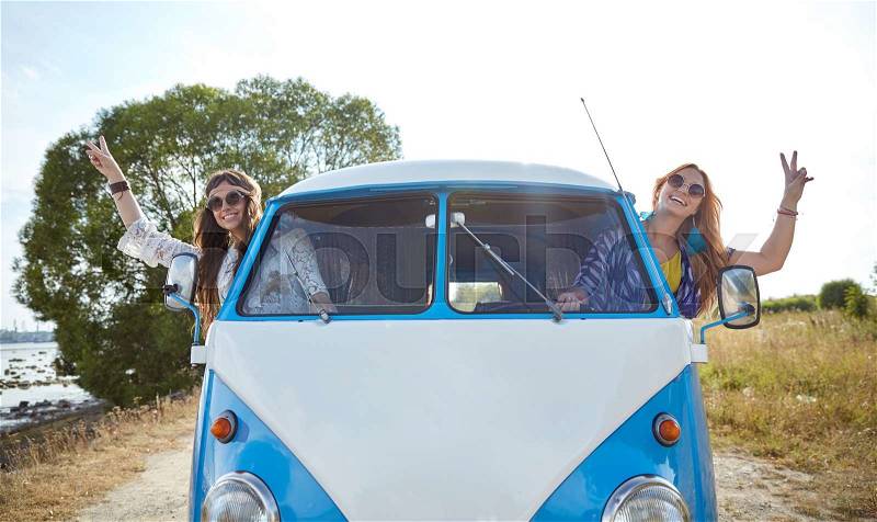 Summer holidays, road trip, vacation, travel and people concept - smiling young hippie women driving minivan car and showing peace gesture, stock photo