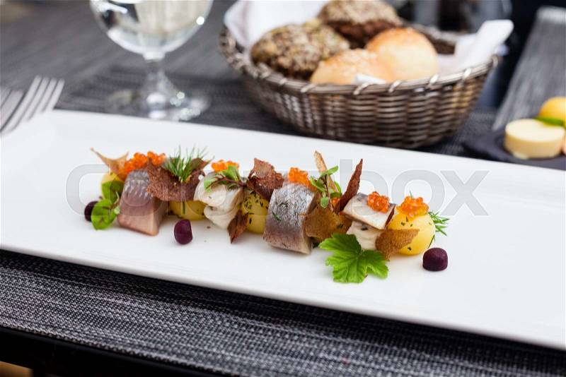 Salted and marinated herring on creamy cheese, beer and black bread chips, potatoes and red caviar, stock photo