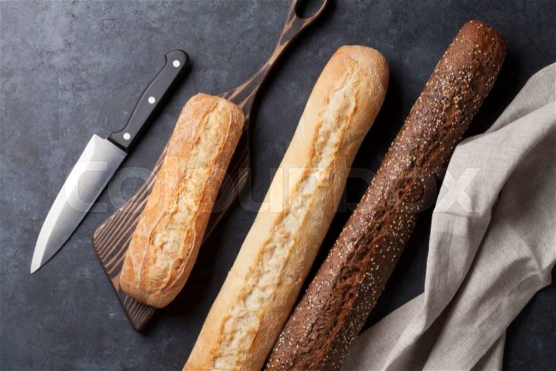 Mixed breads and knife on stone table. Top view, stock photo