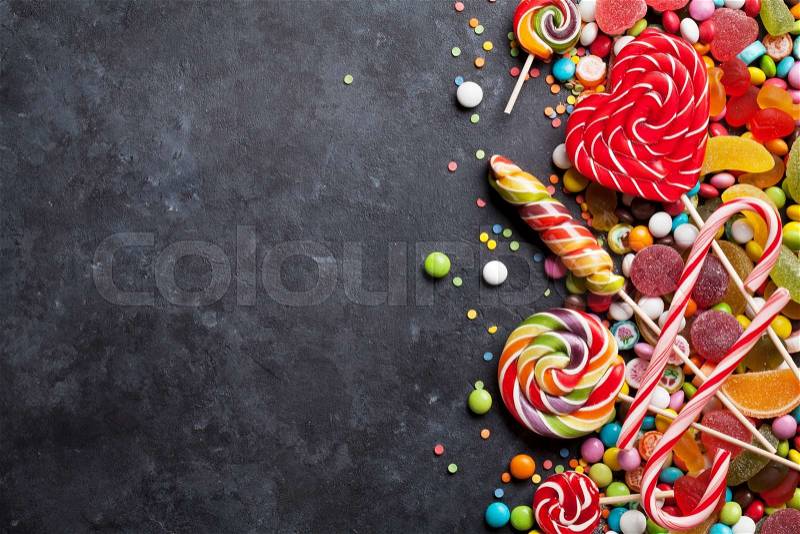 Colorful candies, jelly and marmalade over stone background. Top view with copy space, stock photo