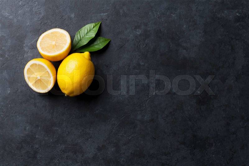 Fresh ripe lemons on dark stone background. Top view with copy space, stock photo