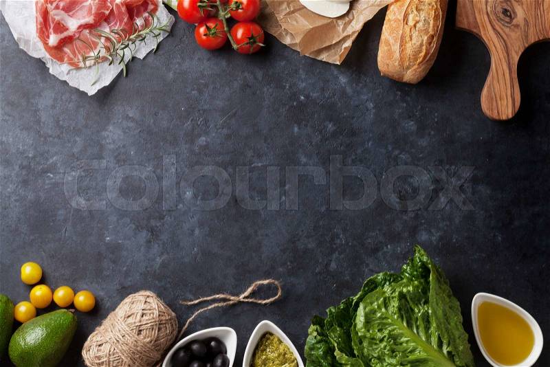 Ciabatta sandwich cooking with romaine salad, prosciutto and mozzarella cheese over stone background. Top view with copy space, stock photo