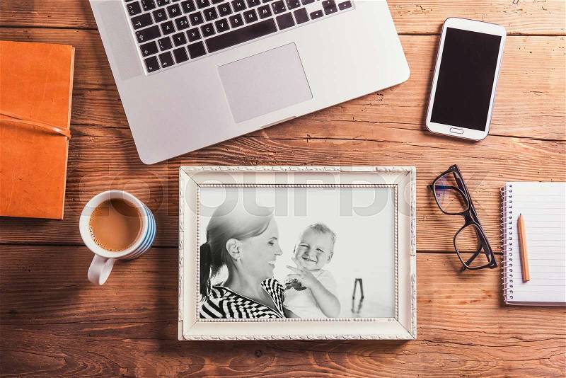 Mothers day composition. Black-and-white photo in picture frame. Office desk. Studio shot on wooden background, stock photo