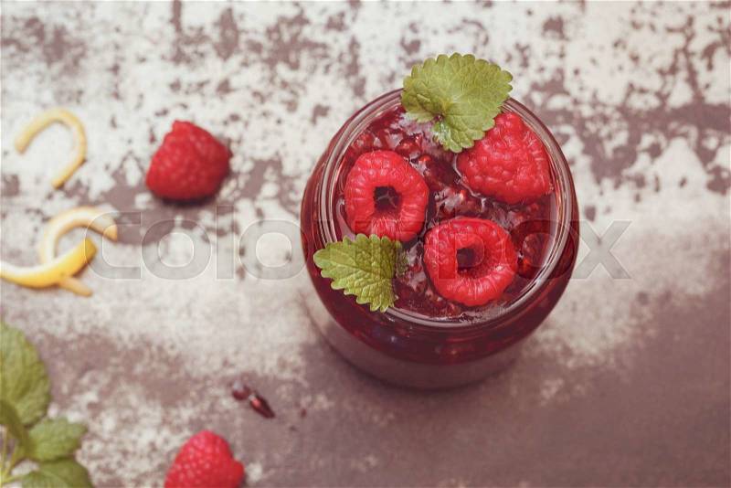 Raspberry Jam. A jar of homemade raspberry jam and fresh raspberries. Macro, selective focus, top view, vintage toned image, blank space, stock photo
