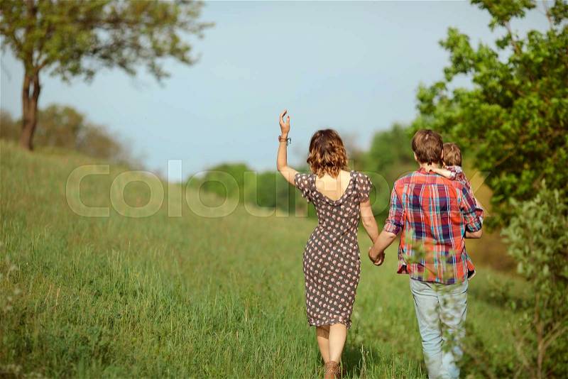 Photo of a young family enjoying a stroll in the park on a sunny summer day, stock photo