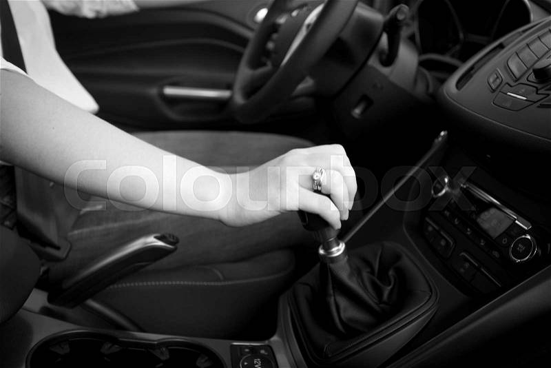 Closeup black and white photo of female driver shifting gear stick, stock photo