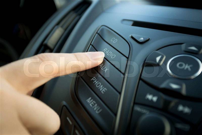 Closeup photo of female finger pressing radio button on car control panel, stock photo