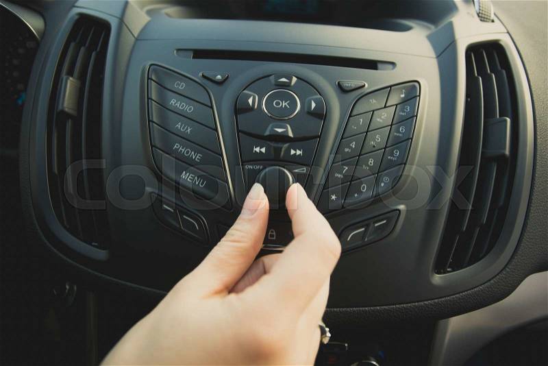 Closeup photo of woman adjusting car stereo system, stock photo